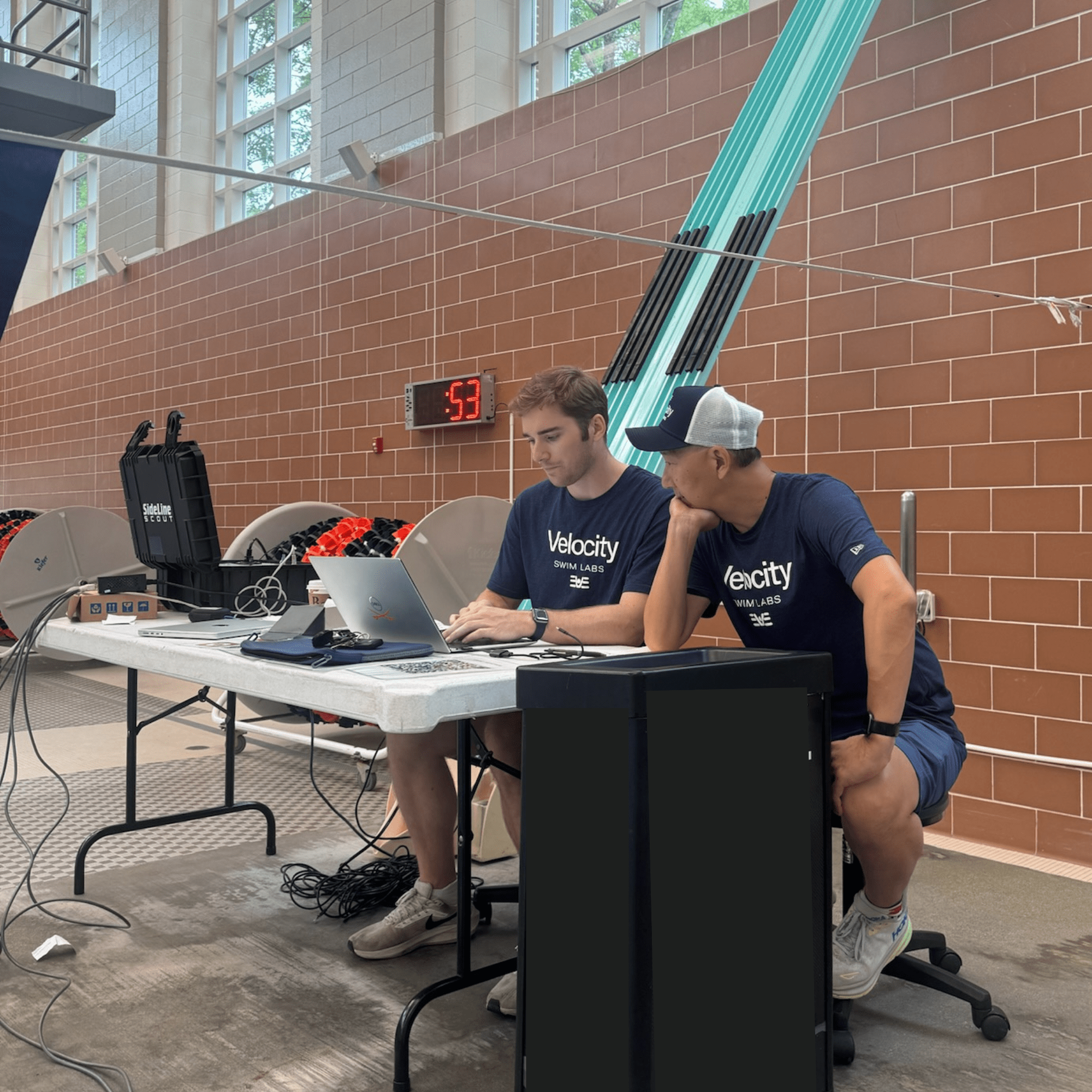 Velocity team members analyzing swim data on laptops