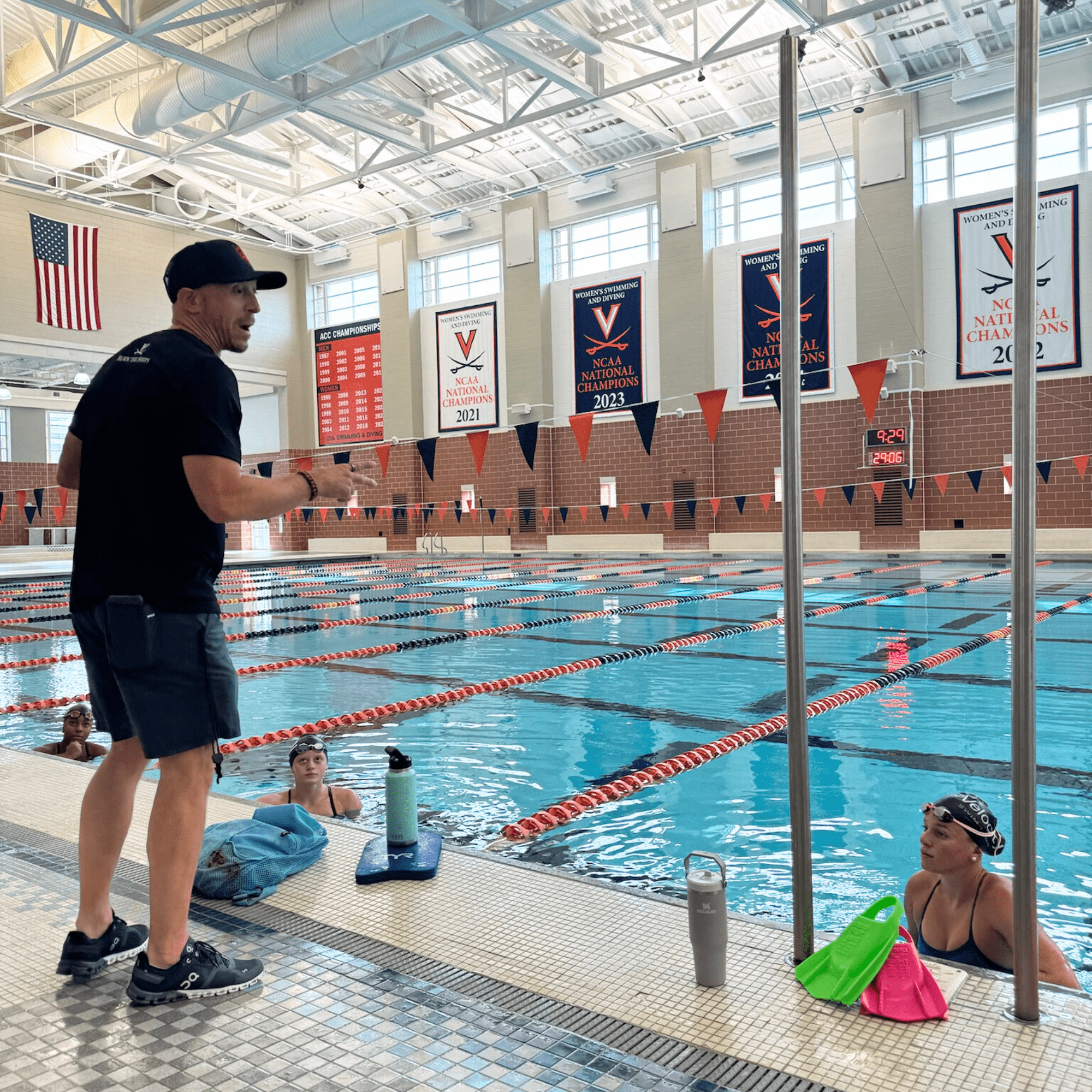 Todd DeSorbo coaching swimmers poolside at UVA with championship banners visible